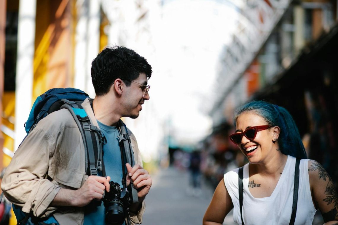 Smiling man and woman enjoying a conversation outdoors, capturing a candid moment.