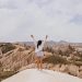 A woman raises her arms in celebration amidst the stunning landscapes of Cappadocia.